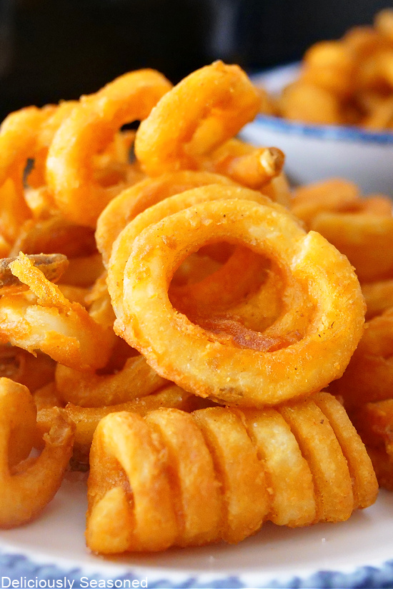 A close up photo of curly fries on a white plate.