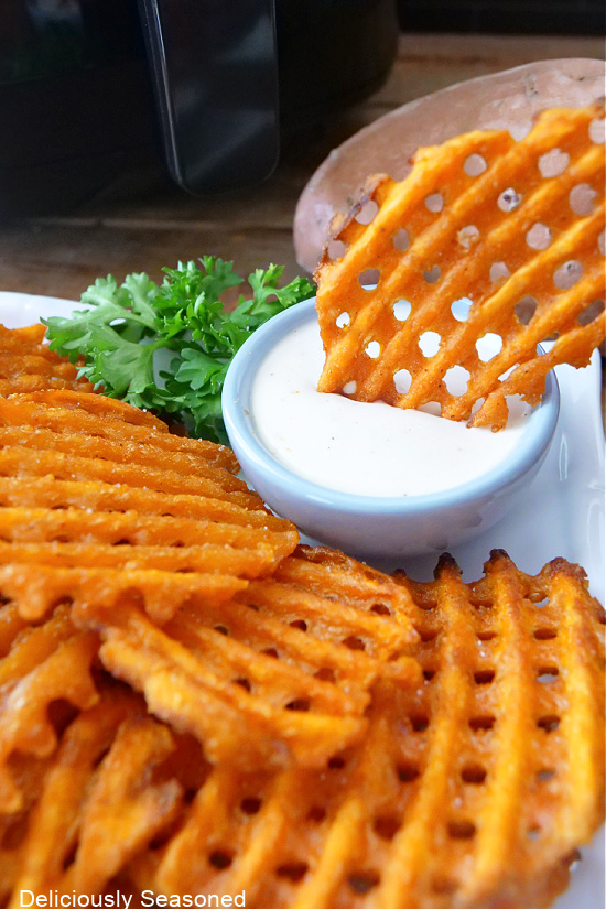 A waffle fry being dipped in a small bowl of ranch dressing.