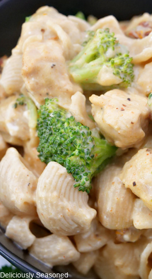 A close up photo of pasta with chicken and  broccoli florets and a creamy sauce covering it.