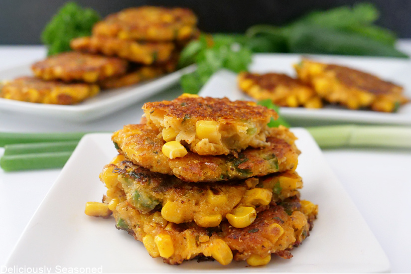 A landscape photo of four fritters stacked up on a plate.