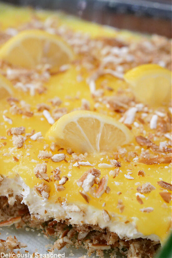 A close-up picture of lemon pretzel dessert topped with crumbled pretzels and lemon slices.