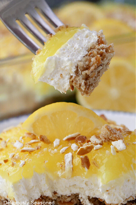 A close up of a fork with a bite of a lemon cream cheese dessert.