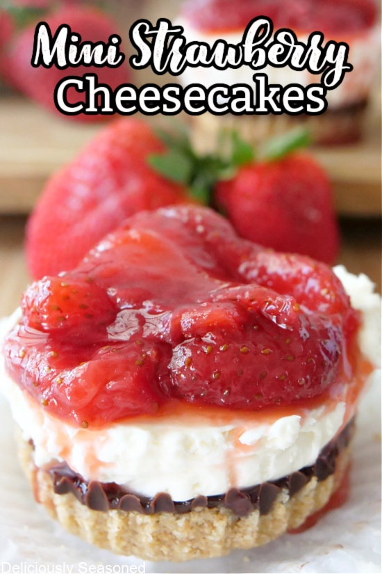 A mini cheesecake on a white plate with strawberries on top and fresh strawberries in the background with the title at the top of the picture.