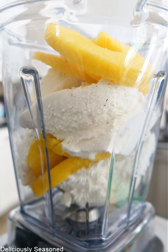 A Vitamix container filled with ice cream and slices of pineapple.