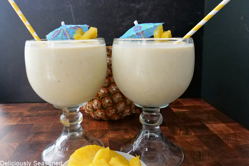 Two large glasses with pineapple milkshake in them.