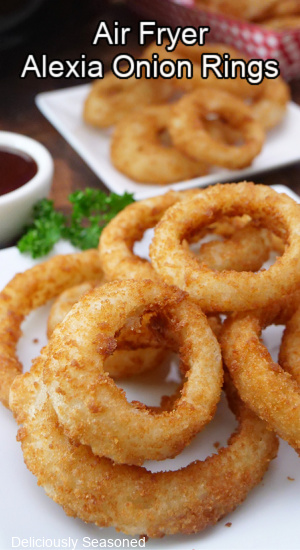 Crispy onion rings stacked up on a white plate.