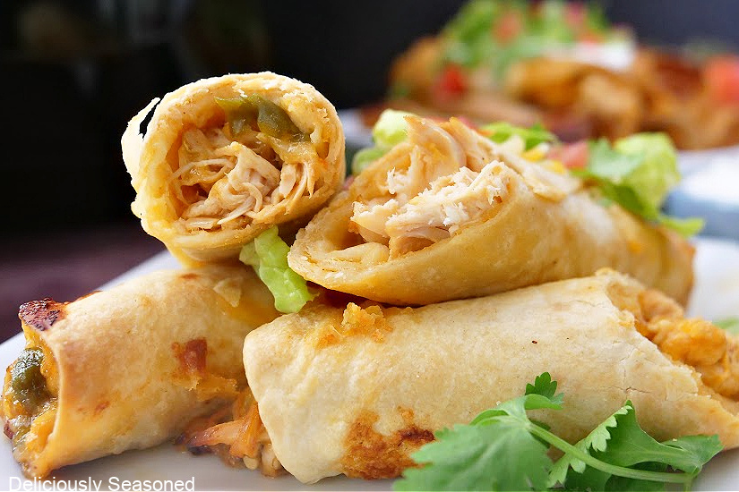 A close-up picture of air fryer flautas cut in half and stacked on top of each other with parsley in the foreground.