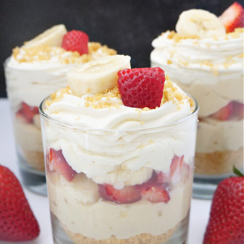 Three glasses filled with banana parfait, topped with fresh strawberries.