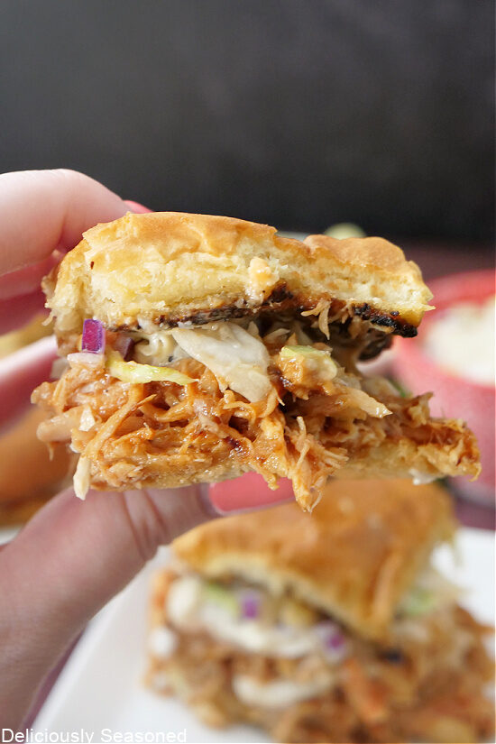 A close up of a chicken slider with a bite taken out of it.