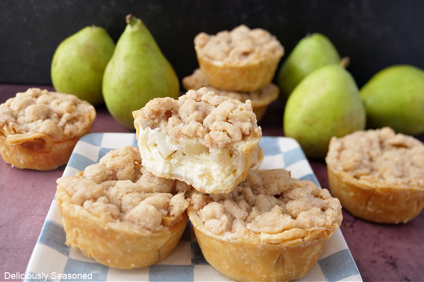 A landscape photo of mini pear pies on a plate with five green pears in the background.