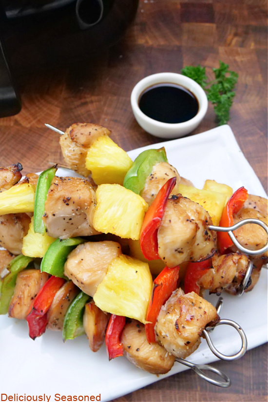 An overhead photo of chicken kabobs on a white plate.