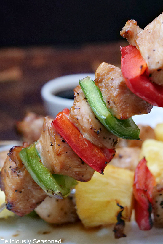 A close up photo of a chicken kabob being held up.