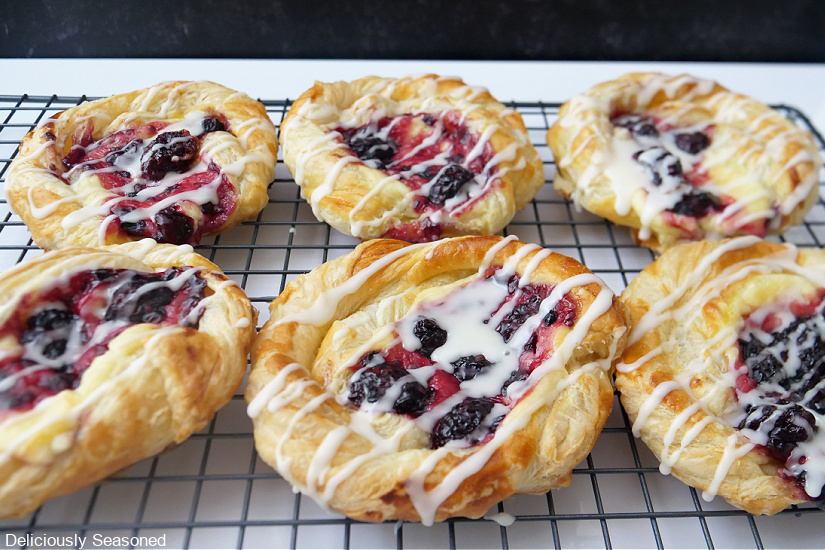 Six blackberry cream cheese pastries on a wire rack.