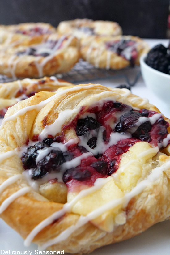 A close up of a pastry filled with cream cheese and blackberries.
