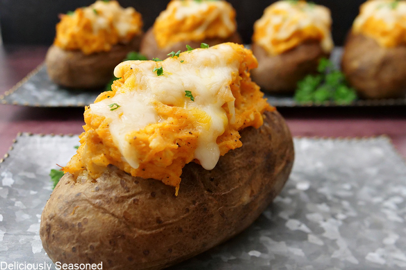 A close up photo of a potato filled with buffalo chicken and topped with melted cheese.