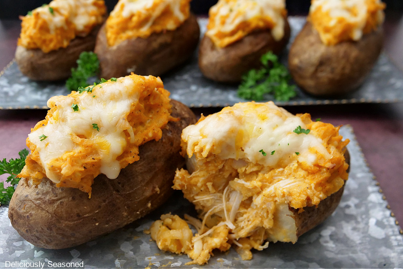 A baked potato cut in half, showing the tender buffalo chicken and cheese.