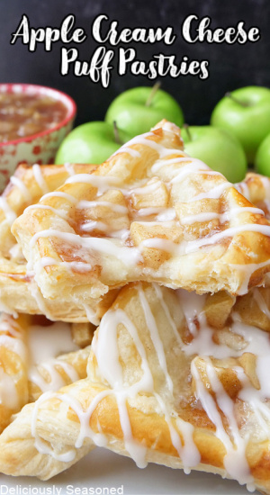 Apple puff pastries stacked up on a plate with Granny Smith apples stacked in the background.