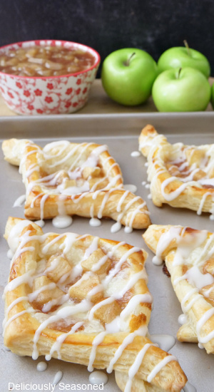 Four puff pastry on a cookie sheet, drizzled in a glaze.