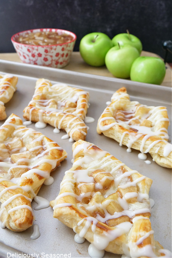 A cookie sheet lined with puff pastries, all with a glaze drizzled over the top.