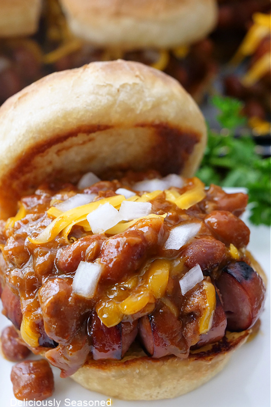 A close up of a chili dog slider on a white plate.