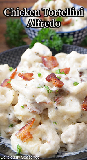 A close up of a serving of pasta with chicken, tortellini and bacon in a creamy Alfredo sauce.