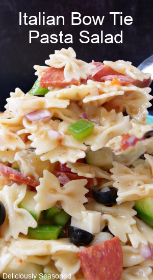 Bow tie pasta salad with olives, bell peppers, pepperoni, and salami, all mixed with farfalle noodles.