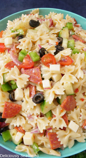 An overhead photo of Italian bow tie pasta salad in a large blue bowl.