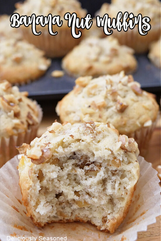 A close up of a banana muffin with a bite taken out of it with more muffins in the background.