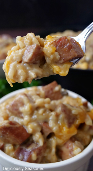 A spoonful of sausage and rice in a cheesy sauce.