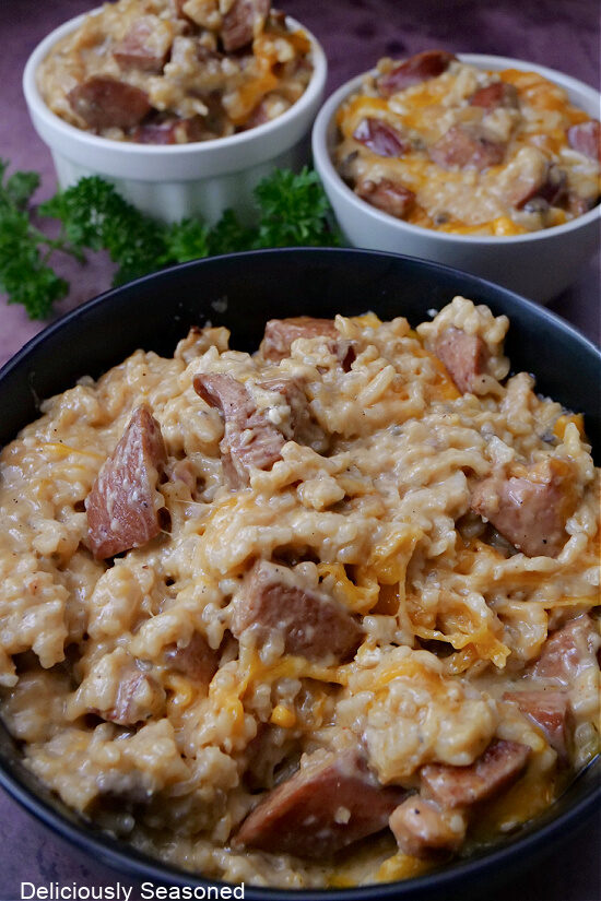 Three bowls filled with cheesy sausage and rice casserole.