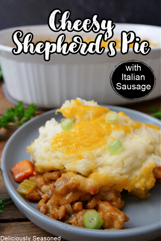 A white casserole dish in the background of a blue plate with a serving of cheesy shepherd's pie on it.