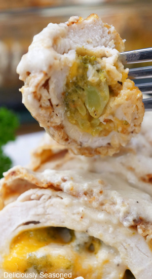 A close up of a bite of chicken cordon bleu with broccoli and cheese.