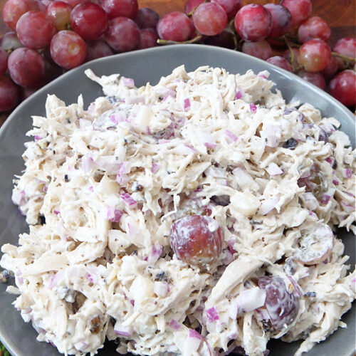 A big gray bowl full of chicken salad with walnuts and grapes.