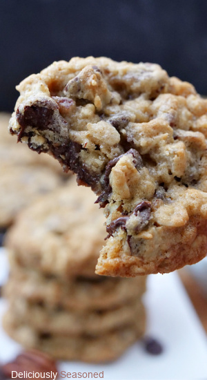 A oatmeal chocolate chip pecan cookie being held up with a bite taken out of it.