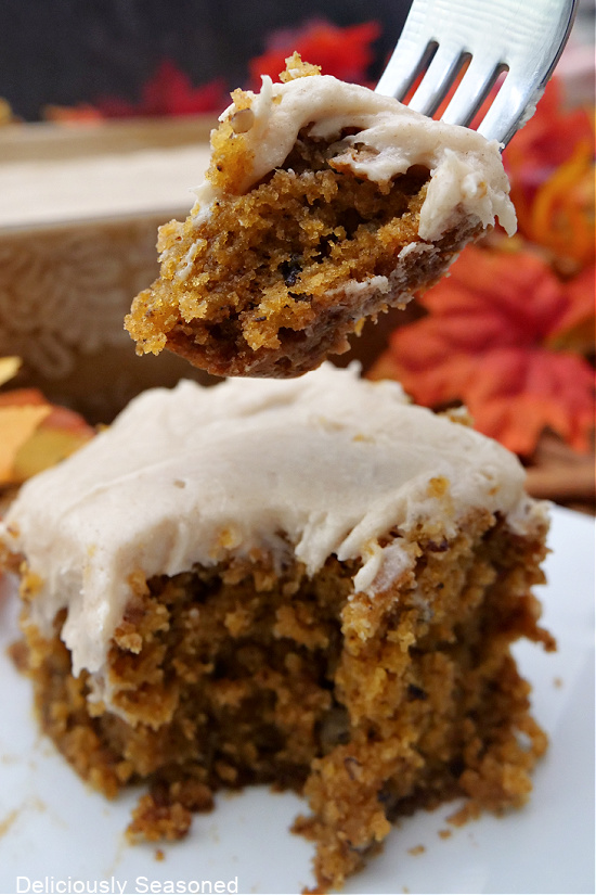 A bite of pumpkin cake on a white plate with a bite on a fork.