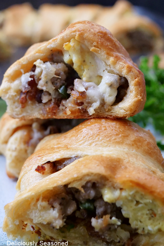 A close up photo of a breakfast pastry filled with cheese, sausage, and eggs.