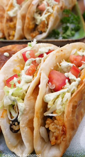 A close up of two southwest chicken tacos with more tacos in the background.