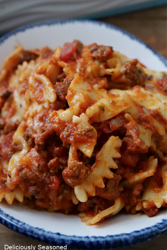 A close up photo of a serving of baked bowtie pasta covered in a meat sauce.