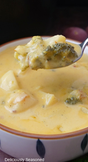 A spoonful of broccoli cheddar soup with potatoes.