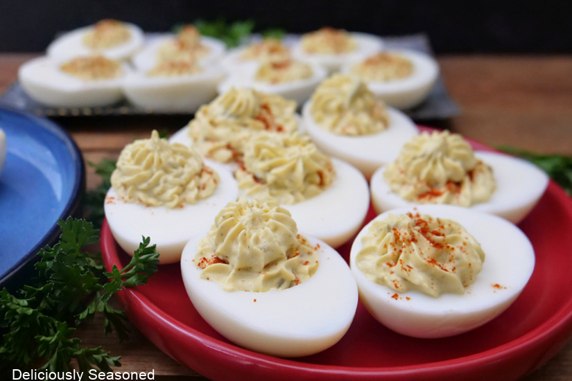 A small round red plate with deviled eggs on it.