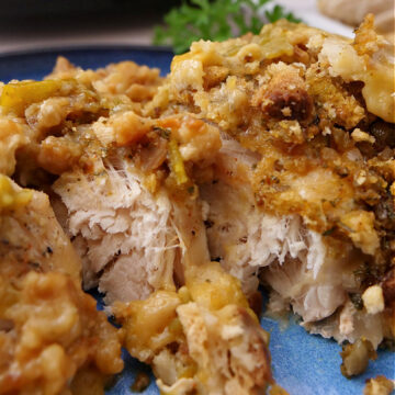 Chicken topped with stuffing on a blue plate.