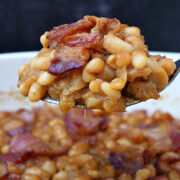 A spoonful of old-fashioned Boston baked beans held up over a dish of more.