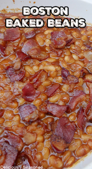 A close up of a white baking dish with baked beans in it after being pulled from the oven.