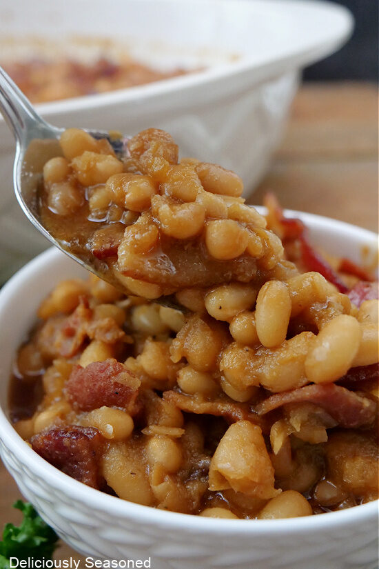 A small white bowl with a spoonful of baked beans on it.