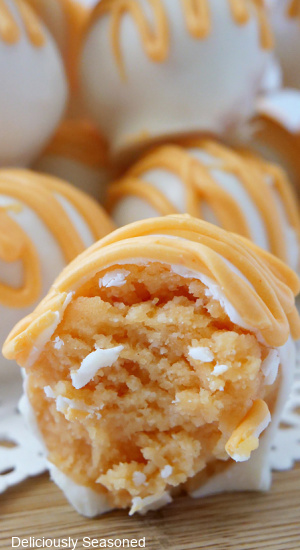 A close up of an orange cake ball with a bite taken out of it.