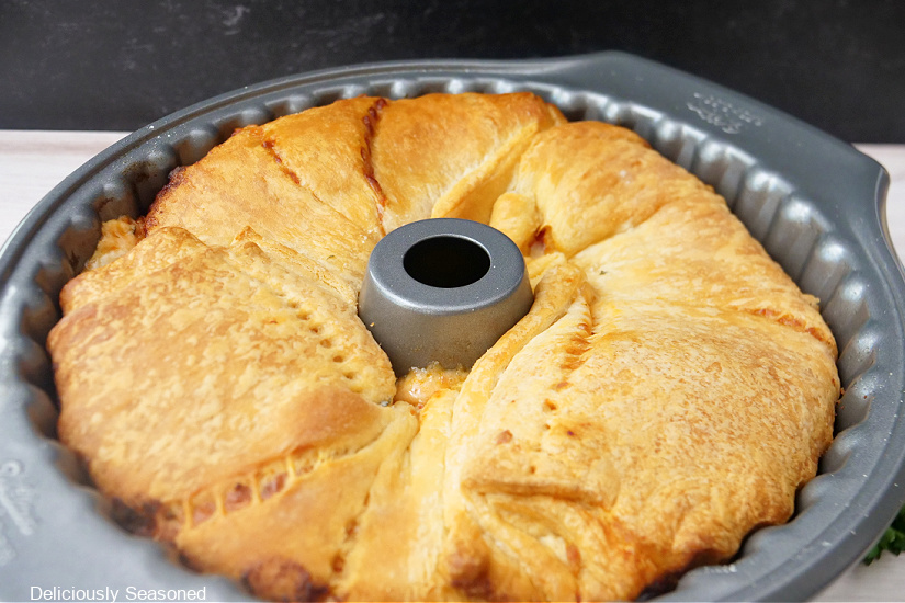 A Bundt Pan showing three crescent rolls stuffed with pepperoni pizza ingredients after being pulled from the oven.