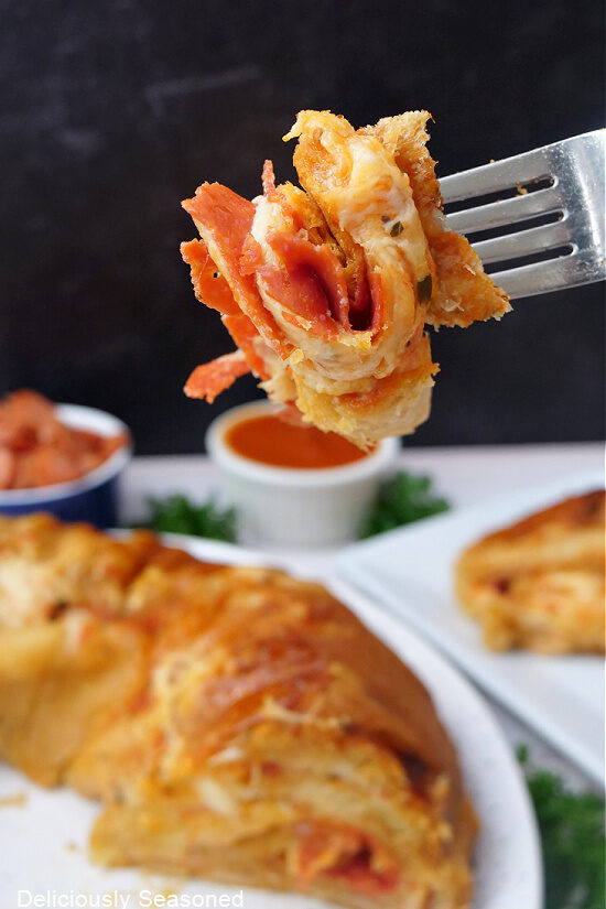 A close up of a bite of pepperoni pizza crescent rolls on a fork.