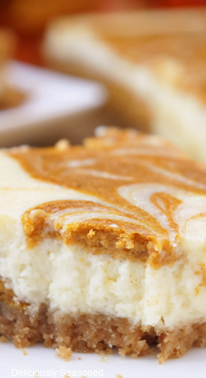 A close up of a piece of pumpkin cheesecake bars.