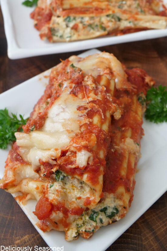 Two sausage and spinach manicotti shells on a white plate.