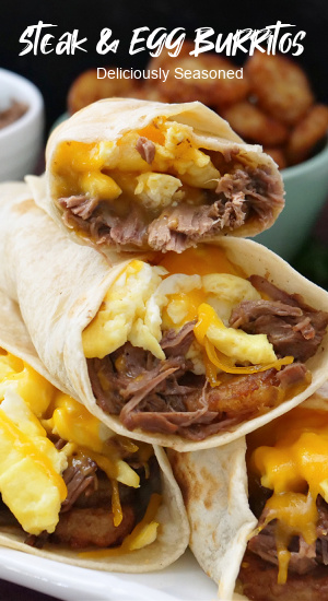 Four steak and egg burritos stacked up on a white plate.